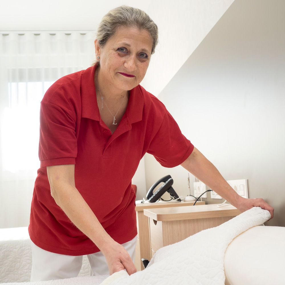 Una de las trabajadoras de la residencia haciendo una cama